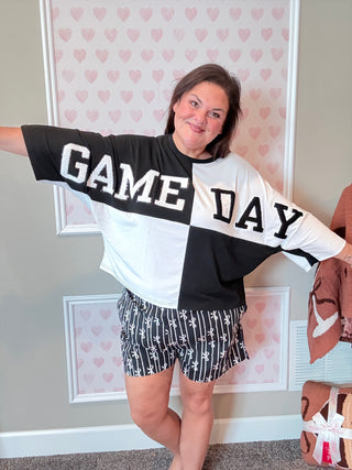 Front view of a black color block top with chenille football patches and sequin outline, styled with a mom crop fit – perfect for game day.