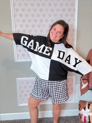 Front view of a black color block top with chenille football patches and sequin outline, styled with a mom crop fit – perfect for game day.