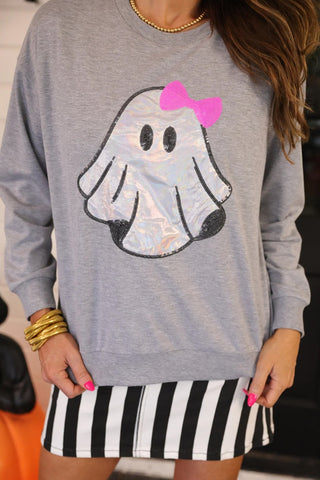 Gray sweatshirt with a ghost design and pink bow, worn by a person.