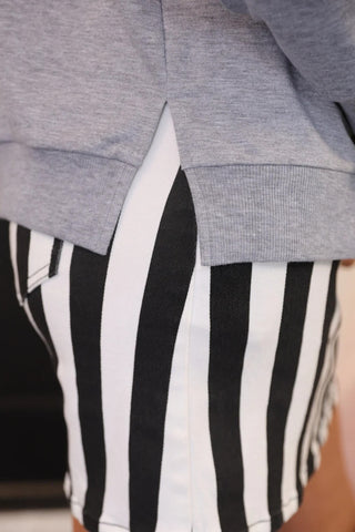 Gray sweatshirt over black and white striped shorts with a blurred background
