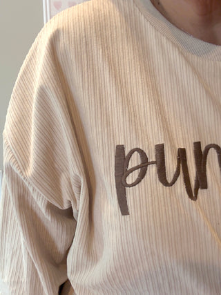 Beige ribbed sweater with 'pun' text on a neutral background