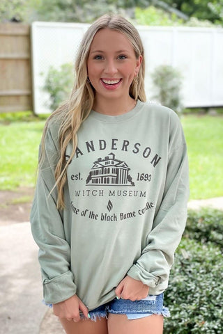 Woman wearing a light green sweatshirt with text and graphics, standing outdoors.