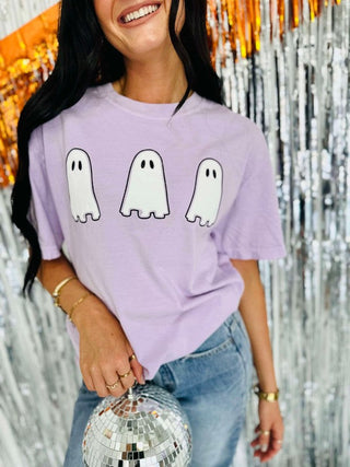 Person wearing a purple t-shirt with ghost designs against a festive background
