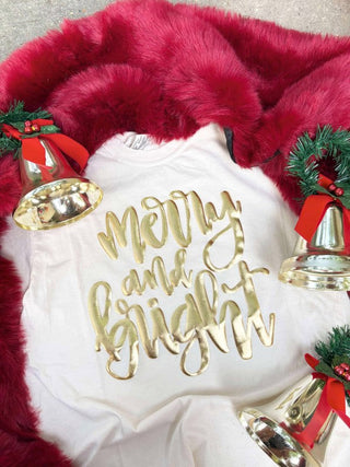 White pillow with 'Merry and Bright' text, surrounded by red fur and Christmas decorations including bells and greenery.