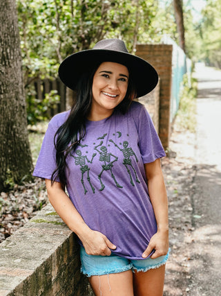 Woman wearing a purple t-shirt with skeleton designs outdoors