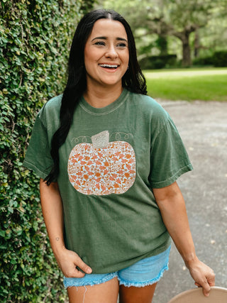 Woman wearing a green t-shirt with a pumpkin design outdoors.
