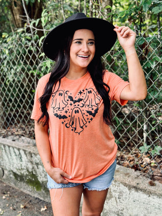 Woman wearing a coral t-shirt with black graphic design outdoors.