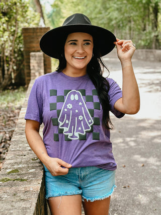Woman wearing a purple t-shirt with a graphic design outdoors