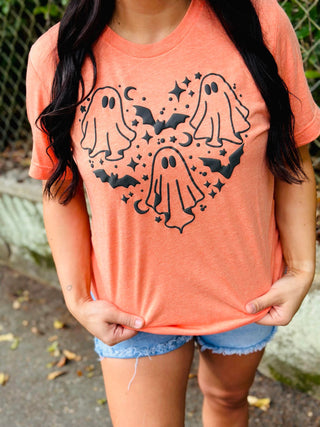 Person wearing a coral t-shirt with ghost designs outdoors