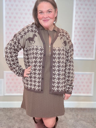 Woman wearing a patterned cardigan over a dress with a horse design.