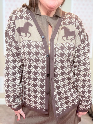 Person wearing a patterned cardigan with horse designs on a neutral background