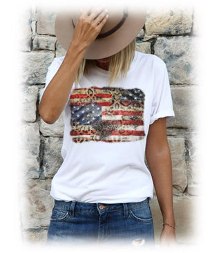 Person wearing a white t-shirt with an American flag design against a stone wall.