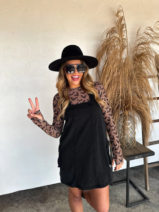 Black sheer mesh long sleeve top with allover bat print, featuring a crew neckline and thumbhole detail. Perfect for layering under cardigans, vests, or sweaters for a trendy, spooky-chic look.