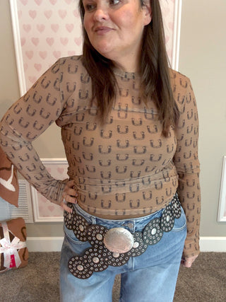 Model wearing the Black Horseshoe Mesh Top with thumbhole sleeves and a fitted silhouette, styled with denim jeans for a trendy western-inspired fall look.