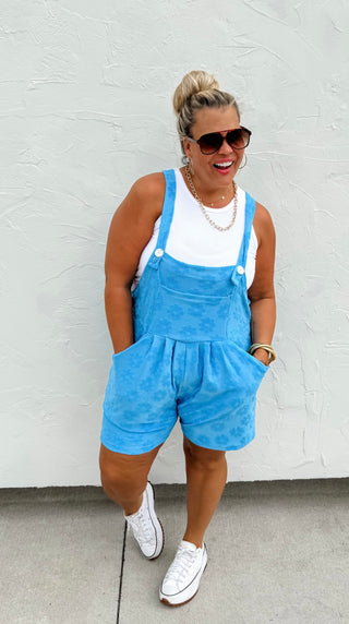 Woman wearing the Cambrie Pocket Romper, styled casually with sneakers for a relaxed, chic look.