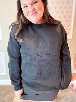 Person wearing a black sweatshirt with ghost embossed designs and 'BOO' text.