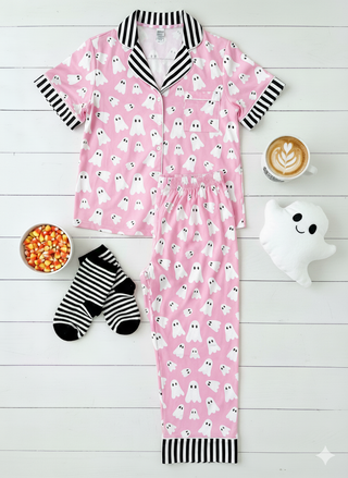Pink pajama set with ghost pattern on a white wooden floor.