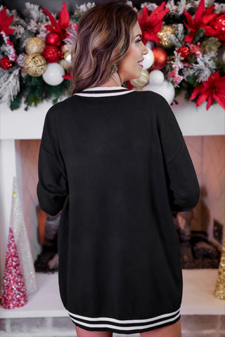 Person wearing a black dress with white stripes in front of a decorated Christmas fireplace.
