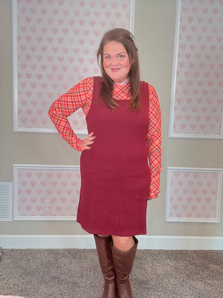 Burgundy ribbed jumper dress with soft, stretchy fabric — flattering fit perfect for layering with mesh tops or sweaters for cozy fall style.