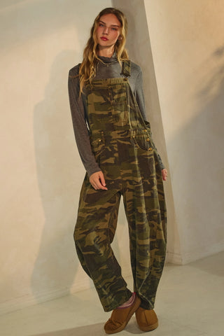Person wearing a camouflage overalls outfit against a plain background