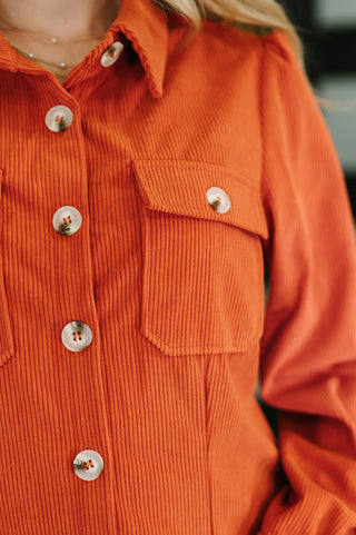 Close-up of an orange corduroy shirt with buttons and a pocket.