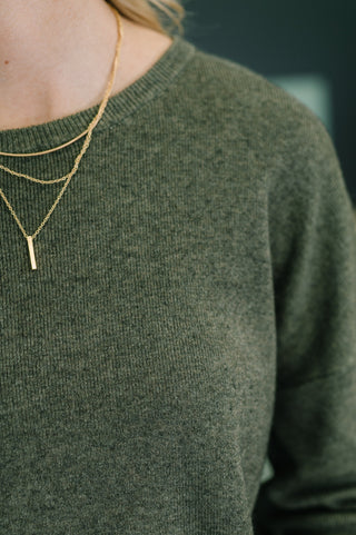 Person wearing a green sweater with a gold necklace