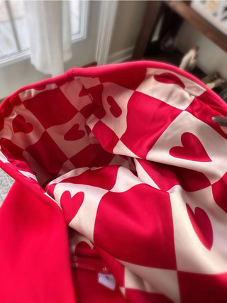 Close-up view of the silky rose gold fabric and checker heart design on the Lina Oversize Hoodie, highlighting its luxurious feel and stylish details.