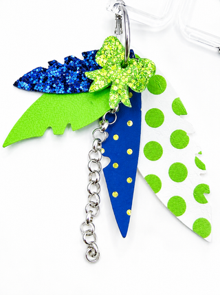 A tropical-themed keyearrings chain featuring a green glitter palm tree, a blue glitter pineapple, a green and white polka dot pineapple, and a silver chain.