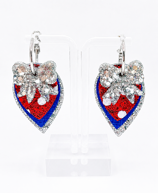 A pair of silver leverback earrings shaped like strawberries, featuring red sequins, blue beaded detailing, white rhinestone accents, and a silver bow on a white background.