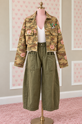 Blakeley Hunting Season women's camo jacket featuring floral camouflage print, embroidered Hunting Season lettering on back, sequin duck chest patch, button-front closure, utility sleeve pockets, and raw hem, available in sizes S/M–3X.