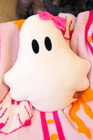 Plush ghost toy on a pink blanket with orange accents