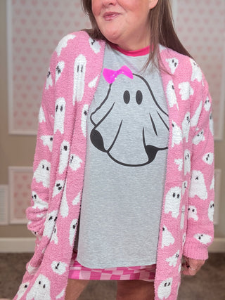 Person wearing a pink cardigan with ghost patterns and a gray shirt with a ghost design.
