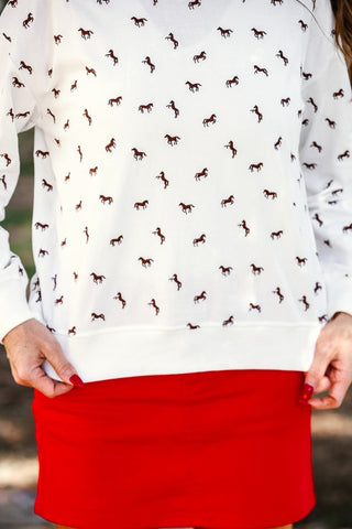 White blouse with horse pattern and red skirt outdoors