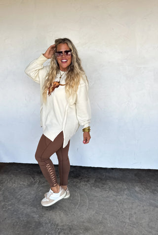 Soft oversized crew pullover with embroidered Highland cow on front, exposed seams, ribbed trim, and split cuff detail — cozy sweatshirt feel with western charm.