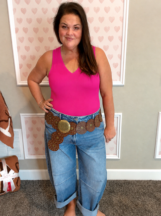 Bright pink v-neck bodysuit with wide leg denim jeans and western belt, trendy boutique style