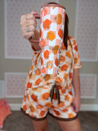 Person wearing a matching outfit with a pumpkin-patterned mug