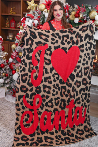Person holding a leopard print blanket with 'I ❤️ Santa' text in a festive indoor setting.