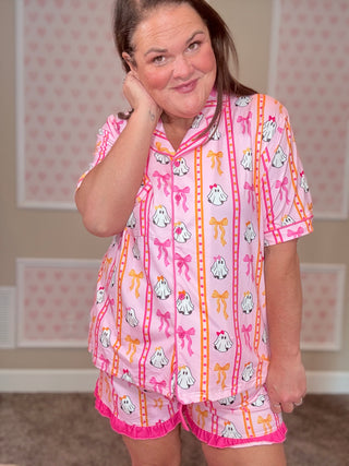Person wearing a pink pajama set with cartoon characters and bows in a room with patterned wallpaper.