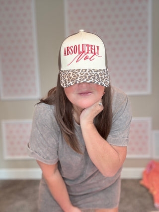 Person wearing a cap with 'Absolutely Not' text in a room with patterned wallpaper.