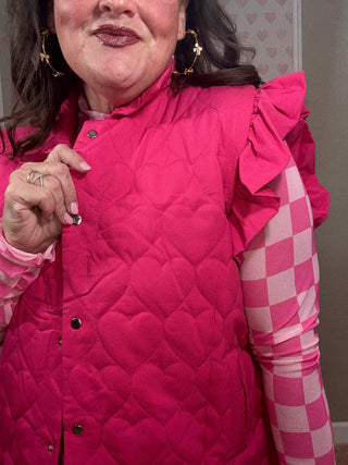 Person wearing a pink quilted vest with a checkered skirt, lying on a surface.