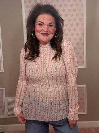 Woman wearing a patterned shirt in a room with framed pictures on the wall.
