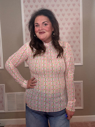 Person wearing a patterned shirt standing in a room with framed pictures on the wall.