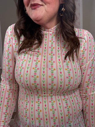 Person wearing a pink and white patterned shirt with long hair.