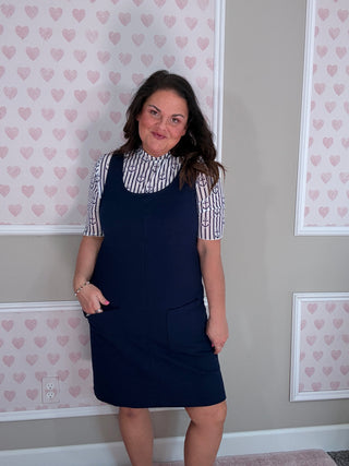 Woman wearing the Rory Ribbed Jumper Dress in navy featuring soft stretchy ribbed fabric and classic scoop neckline.