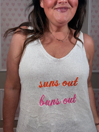 Woman wearing a white tank top with 'sun's out, buns out' embroidered.