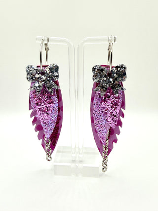 Purple and lavender layered statement earrings with silver glitter bow accent, lavender glitter detail, embossed purple texture, lavender polka dots, and silver chain charm.