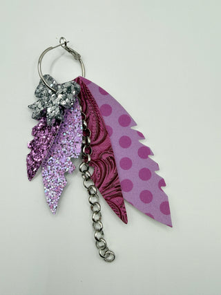 Purple and lavender layered statement earrings with silver glitter bow accent, lavender glitter detail, embossed purple texture, lavender polka dots, and silver chain charm.