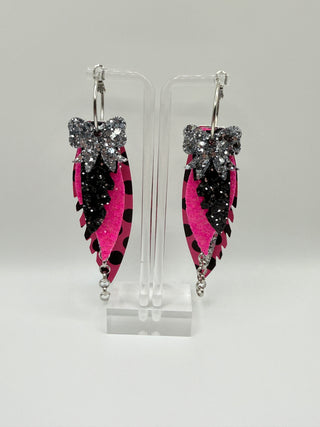 Hot pink and black polka dot statement earrings with silver glitter accents, layered faux leather feather details, silver chain charm, and lightweight boutique design.