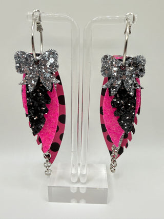 Hot pink and black polka dot statement earrings with silver glitter accents, layered faux leather feather details, silver chain charm, and lightweight boutique design.