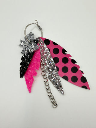 Hot pink and black polka dot statement earrings with silver glitter accents, layered faux leather feather details, silver chain charm, and lightweight boutique design.